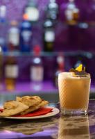 a drink on a table next to a plate of food at The LaLit London in London