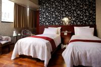 a bedroom with two beds and a wall with flowers at Gene Long Haiy Att Hotel in Chiayi City
