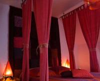 a bedroom with red drapes on a bed at La Grande Mare in Saint-Benoît-des-Ondes