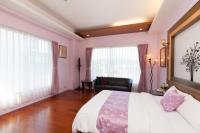 a bedroom with a large bed with pink walls at Chun Feng Cao Tang Homestay in Yuanshan