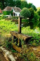 a wooden bench sitting next to a body of water at Au Moulin de La Gorce in La Roche-lʼAbeille