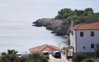 a group of buildings and cars parked next to the water at Dimitra&#39;s Apartment in Votsi