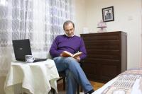 a man sitting in a chair reading a book at Best Room in Town in Karakusunlar Köyü