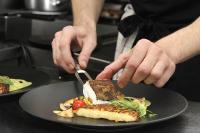 une personne coupant une assiette de nourriture avec un couteau et une fourchette dans l'établissement Logis Hôtel Restaurant Du Labrador, à Saint-Benoît-sur-Loire