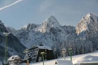 Una montaña cubierta de nieve con un edificio delante. en Hotel Alpina, en Kranjska Gora