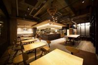a restaurant with wooden tables and chairs and a kitchen at Hotel Cordia Osaka in Osaka