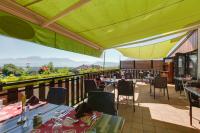 Un restaurante con mesas y sillas en un balcón. en Logis Le Pont de Champ, en Beaucroissant