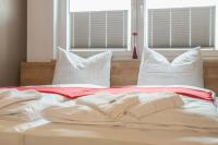 1 cama con sábanas y almohadas blancas y 2 ventanas en My Hostel, en Múnich