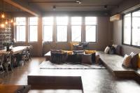 a living room with a couch and a table and windows at Silom Space Hostel in Bangkok
