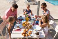 una famiglia seduta a un tavolo che fa colazione di Camping RCN Belledonne a Le Bourg-dʼOisans