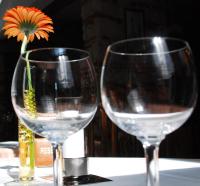 two wine glasses on a table with a flower in a vase at Bawelsberger Hof in Dillingen an der Saar