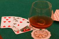a glass of wine sitting next to a playing cards at Hôtel d&#39;Etigny in Luchon