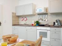 a kitchen with white cabinets and a table and a microwave at Fischerhaus Bremerhaven in Bremerhaven