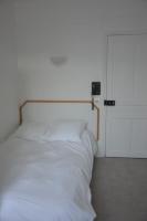 a white bed in a white room with a door at Hôtel De Normandie in Amiens