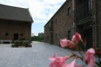 a courtyard with pink flowers in front of a brick building at Hotel Oude Eycke in Maaseik