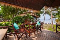 a deck with chairs and a table and a hut at Palm Leaf Resort Koh Tao in Ko Tao