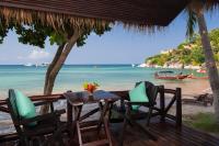 a table and chairs on a beach with the ocean at Palm Leaf Resort Koh Tao in Ko Tao