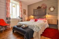 a bedroom with a large bed and a red chair at La Maison Bizienne Guérande in Guérande