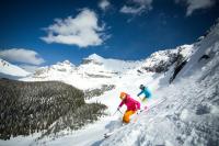 two people skiing down a snow covered mountain at Sunshine Mountain Lodge in Banff