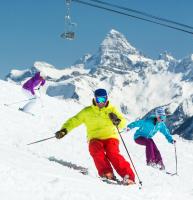 three people are skiing down a snow covered mountain at Sunshine Mountain Lodge in Banff