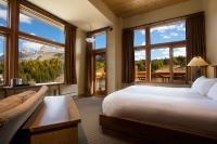 a bedroom with a large bed and large windows at Sunshine Mountain Lodge in Banff