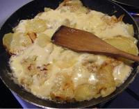 a pan of food with a wooden spoon in it at La Maison des Chats in Saint-Mary-le-Plain