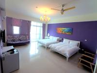 a bedroom with two beds and a purple wall at Eik Forest B&amp;B in Taitung City