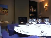 a white table with wine glasses and blue chairs at Hôtel Le Cobh in Ploërmel