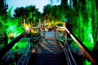 un puente sobre un estanque con luces verdes en Jardines de Casablanca, en Caravaca de la Cruz