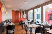 Un restaurante con mesas, sillas y ventanas. en Hôtel Aux Vieux Remparts, en Provins