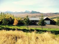 a house in a field with mountains in the background at Ásar Guesthouse in Eyjafjaroarsveit