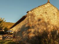 a large stone building with tables and an umbrella at Amazing Holiday Home in Cazals with Terrace in Cazals