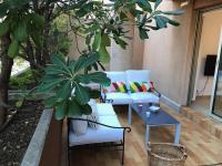 a patio with white chairs and a table and trees at Dans un écrin de verdure in Hyères