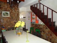 a table with a vase of flowers on a table with a stone wall at Casa com Piscina Paraty in Paraty