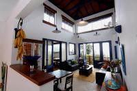 a living room with white walls and windows and a table at Pousada DiMari in Boicucanga