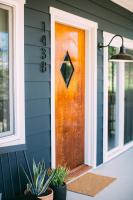 an orange door on a blue house with plants at Noon on Sunset Hill in Los Angeles
