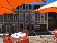 una mesa con sombrillas naranjas frente a un edificio en Le Dome, en Arras