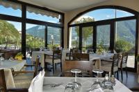 een restaurant met witte tafels en stoelen en grote ramen bij Hotel Sole in San Siro