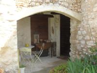 an archway in a stone building with a table and chair at Le Mas De La Chérine in Quinson