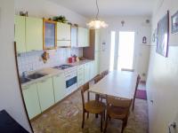 a kitchen with green cabinets and a table and chairs at Condominio Sole - Agenzia Cocal in Caorle