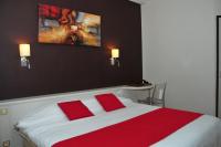 a bedroom with a large bed with two red pillows at Cit&#39;Hotel Europeen in Angoulême