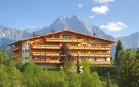 un edificio en una colina con montañas al fondo en Hotel Seelos, en Seefeld in Tirol