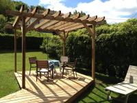a wooden deck with chairs and a wooden pergola at Chalet de Grettery in Saulxures-sur-Moselotte