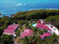 an aerial view of a resort with pink roofs and the ocean at La Rose du Bresil Marie-Galante in Capesterre
