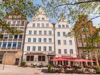 リューベックにあるHotel Jensenの白い大きな建物(テーブルと赤い傘付)