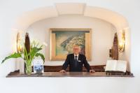 a man in a suit sitting at a desk at Hotel Poseidon in Positano