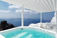 a white bath tub with a view of the ocean at Tholos Resort in Imerovigli
