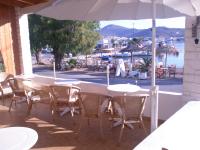 Una mesa con sillas y una sombrilla en un patio. en Captain&#39;s House Hotel, en Skala
