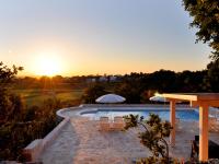 una piscina con sillas y sombrillas al atardecer en B&amp;B Lamie Di Olimpia, en Locorotondo