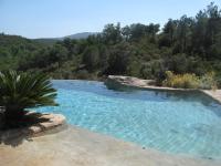 a swimming pool in the middle of a hill with trees at Mas de la Fariole in Caixas